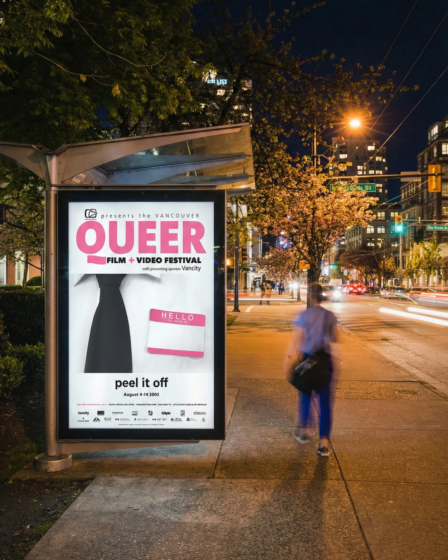 Illuminated bus shelter poster advertisement for the Vancouver Queer Film and Video Festival at night with a blurred pedestrian.